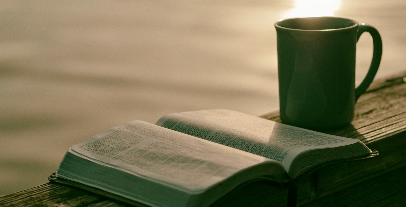 green ceramic mug beside book